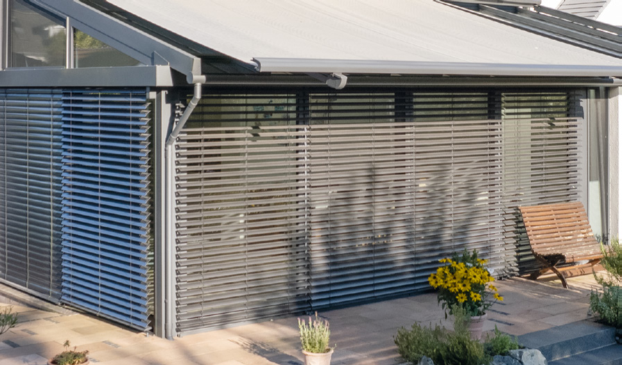 Verstellbare Aluminium-Raffstores an der Glasfassade ermöglichen eine präzise Steuerung des Lichteinfalls und dienen als modernes architektonisches Stilelement.